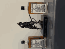 two bottles of leadslingers sit on a shelf next to a statue of a soldier