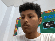 a young man taking a selfie in front of a bulletin board that has the word poetry on it