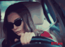 a woman wearing sunglasses is driving a car with effam written on the bottom right