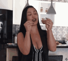 a woman in a black and white striped top is eating a piece of food