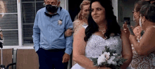 a bride and groom wearing face masks are walking down the aisle .