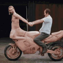 a naked man is sitting on a motorcycle while a man shakes his hand