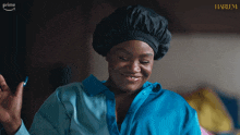 a woman wearing a blue shirt and a black hat is smiling in front of a sign that says harlem