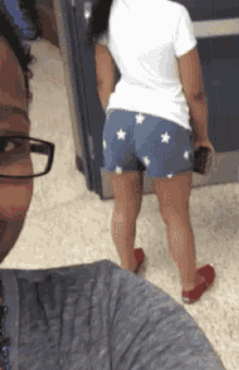 a woman in shorts with stars on them is standing in front of a man wearing glasses