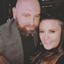 a man with a beard and a woman with long hair are posing for a picture .