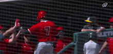 a group of baseball players are giving each other a high five while standing in front of a net .