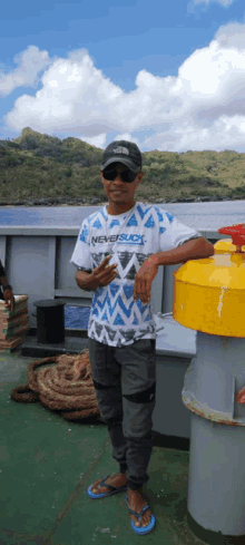 a man wearing a shirt that says never suck stands on a boat