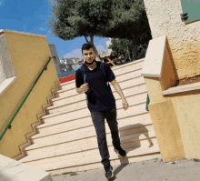 a young man wearing a blue shirt and black jeans is walking down stairs