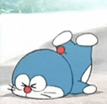 doraemon is laying on its back on the ground with its eyes closed .