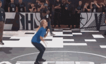 a woman in a blue shirt is squatting on a basketball court in front of a sign that says nhs