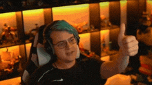 a man with blue hair and glasses is giving a thumbs up