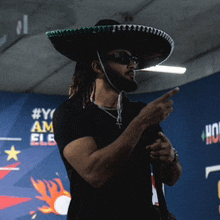 a man wearing a sombrero and sunglasses points to something