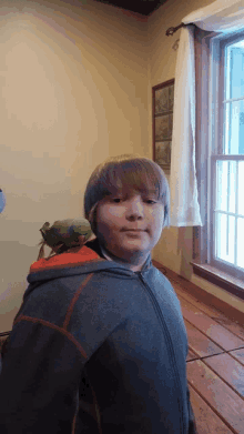 a boy with a parrot on his shoulder looks at the camera