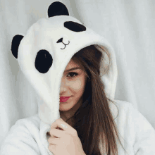 a woman is wearing a panda hoodie with a panda face on the hood .