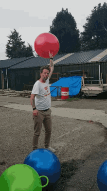 a man holds a red balloon over his head while wearing a t-shirt that says " aviator " on the front