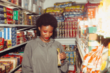 a woman in a grocery store looking at a bag of pringles