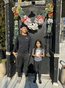 a boy in an under armour shirt stands next to a little girl