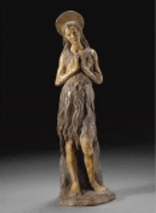 a statue of a woman with long hair and a crown on her head is standing on a table .