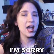 a woman is making a funny face in front of a microphone and saying `` i 'm sorry '' .