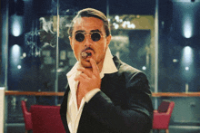 a man in a suit is smoking a cigar and wearing sunglasses