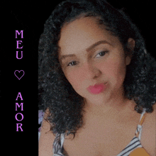 a woman with curly hair stands in front of a sign that says meu amor on it