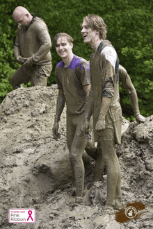 a group of people covered in mud with a pink ribbon