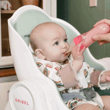 a baby in a high chair with oribel on the side