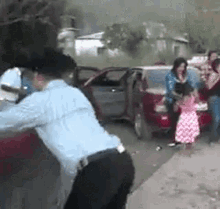 a group of people are standing around a car and a police officer is standing next to a car .