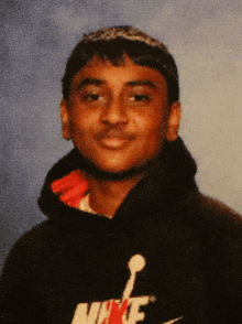 a young man wearing a black nike hoodie poses for a photo