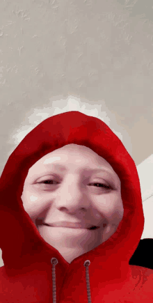 a woman wearing a red hoodie is smiling and making a funny face