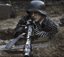 a man in a helmet is holding a machine gun in his hand