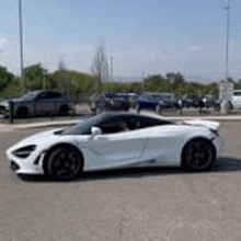 a white sports car is parked in a parking lot next to a truck .