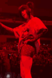 a woman is standing on a stage in front of a crowd in a dark room .