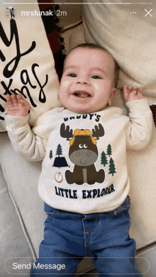 a baby wearing a little explorer shirt is laying on a couch