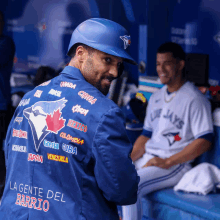 a man wearing a blue jacket that says la gente del barrio on the back