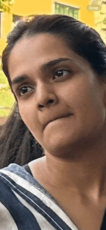 a close up of a woman 's face with a striped shirt on making a funny face .