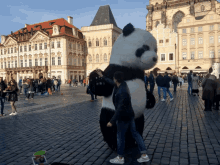 a woman is petting a giant panda bear in front of a building that says ' moscow ' on it