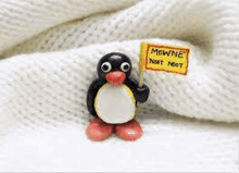 a penguin figurine is holding a sign that says mowne .