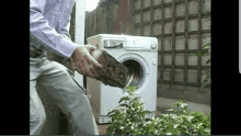 a man is loading a large rock into a washing machine outside