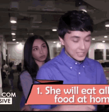 a man and a woman are standing in front of a sign that says she will eat all food at hom