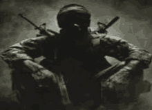 a soldier in a gas mask is kneeling down with two guns on his back .