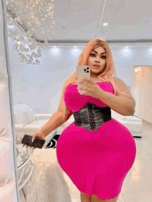 a woman in a pink dress is taking a selfie with her phone