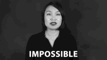 a woman in a black shirt is making a face in front of a black background and the word impossible is visible .