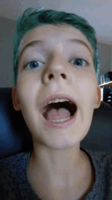 a young boy with green hair has his mouth open and his tongue hanging out