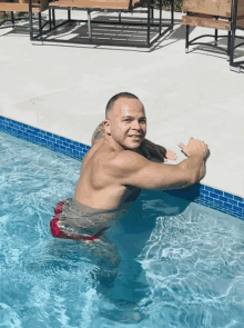 a shirtless man is swimming in a pool