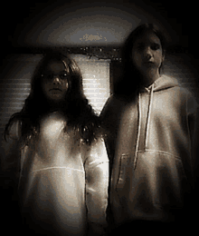 two girls standing next to each other wearing white sweatshirts