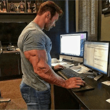 a man with very large muscles is typing on a computer