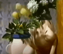 a blurred image of a person holding a bouquet of flowers in a white vase