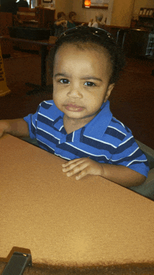 a little boy wearing sunglasses sits at a table