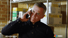 a man is talking on a cell phone in front of a shelf with boxes of bulk white plastic knives